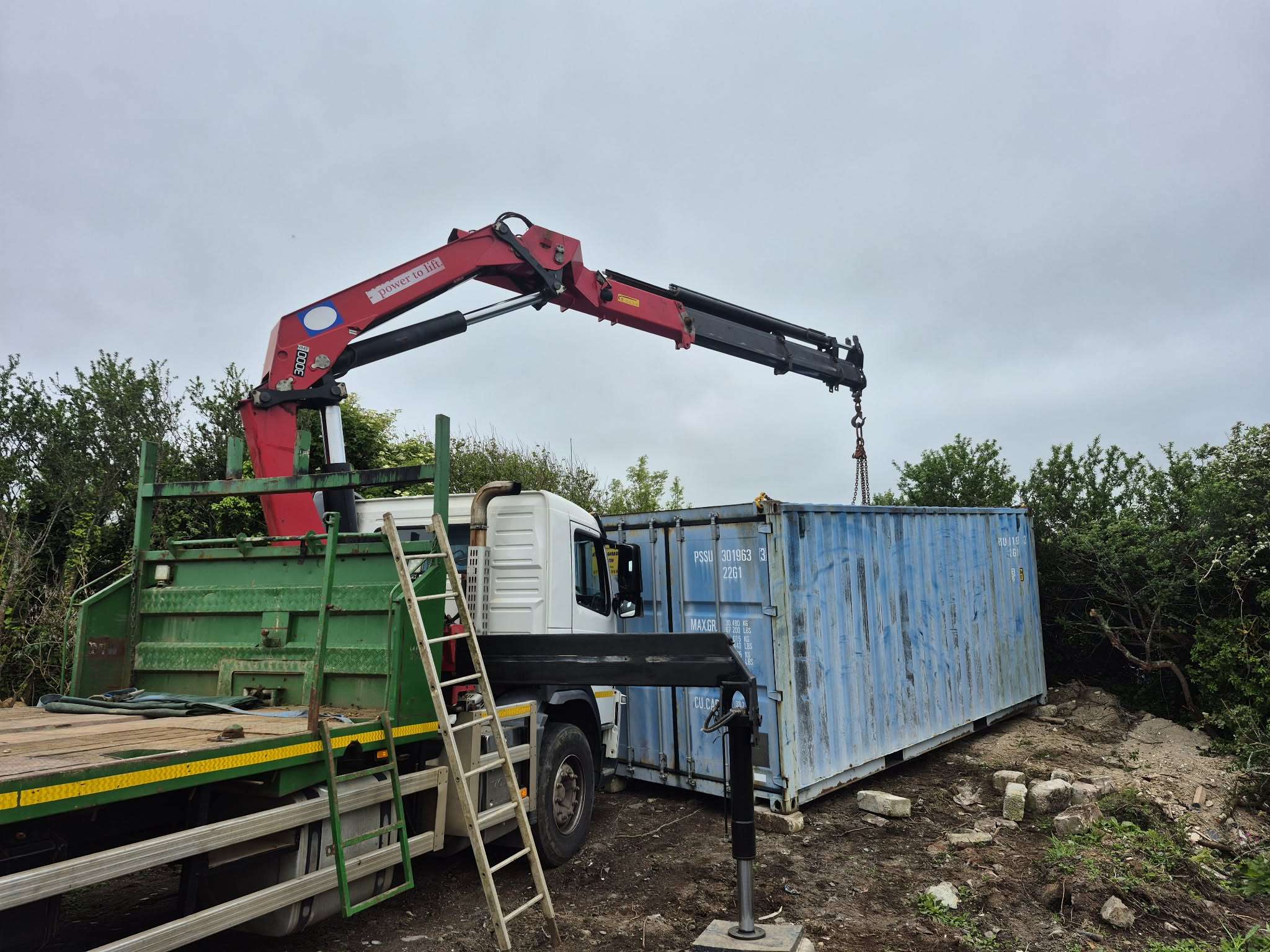 A 20ft container being set down beside the lorry on a site