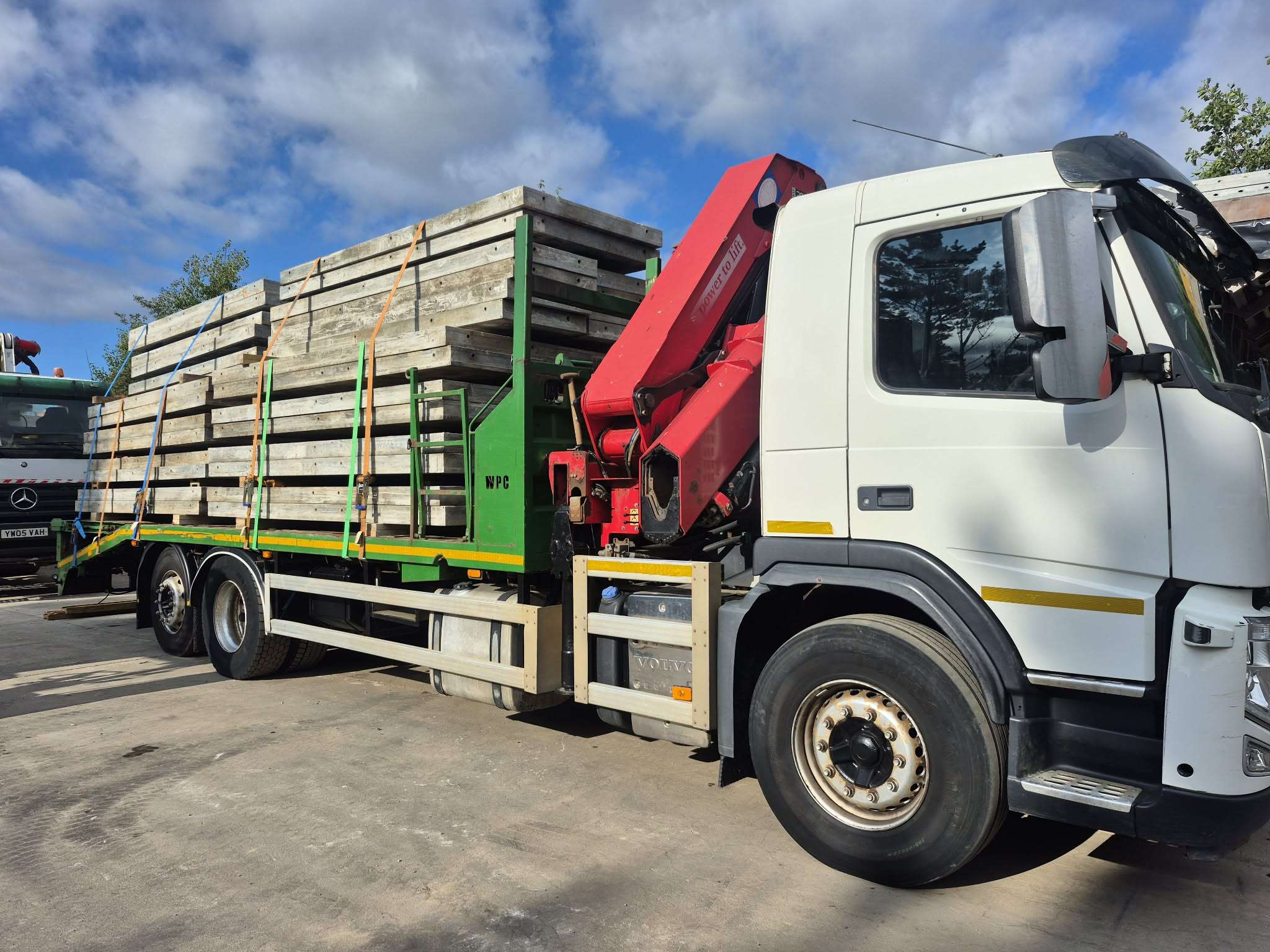The lorry loaded with shuttering panels, red crane folded behind the cab